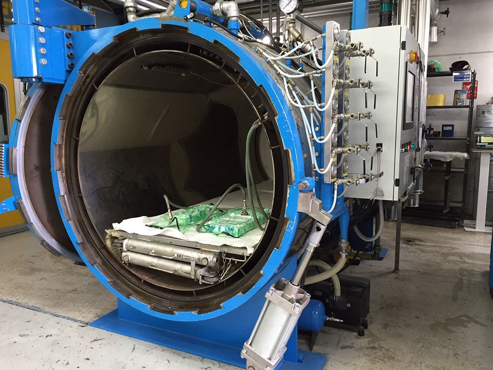 Open industrial autoclave loaded with parts for curing