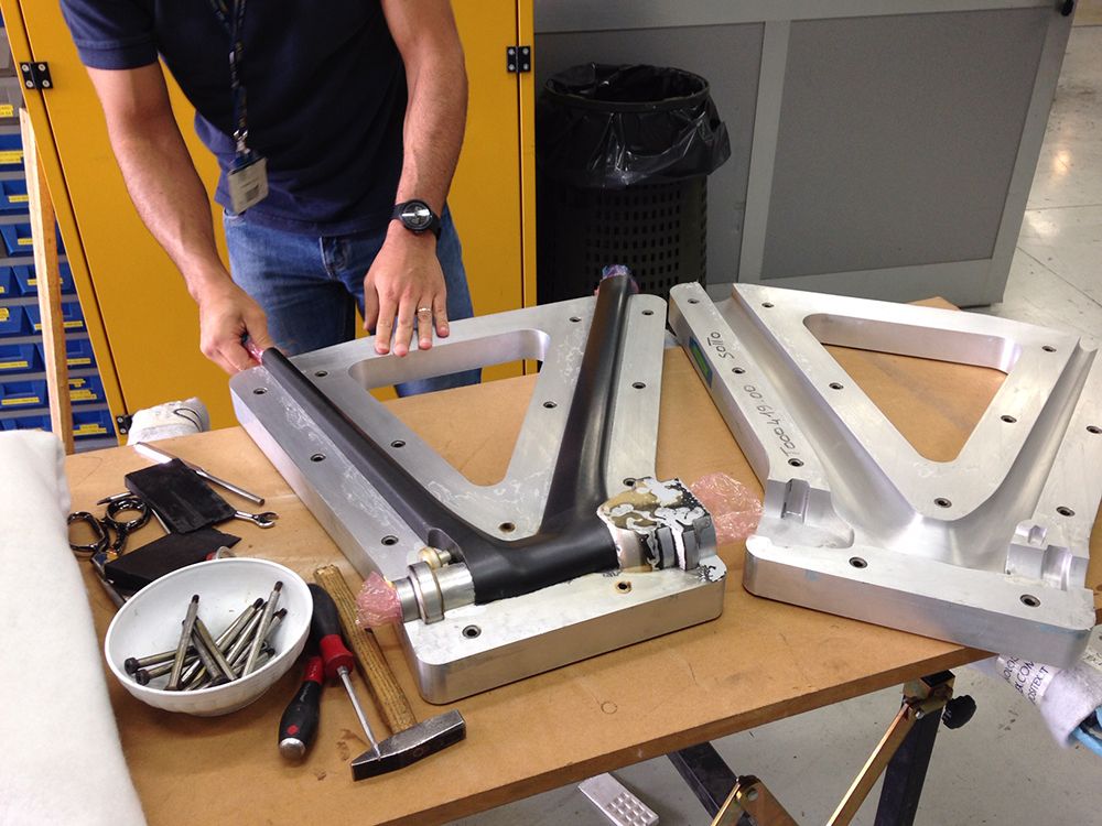 Opening an aluminium mould with a moulded carbon front triangle on a workshop bench